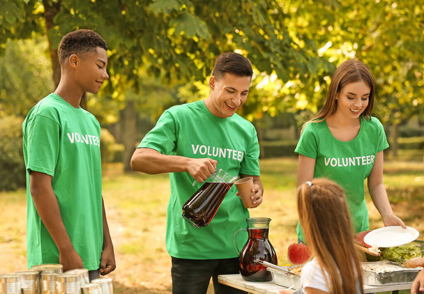 Młodzi wolontariusze dający żywność biednym ludziom na świeżym powietrzu - Zdjęcie, obraz