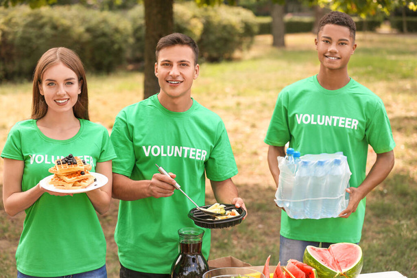 Νέοι εθελοντές με φαγητό για φτωχούς ανθρώπους στο ύπαιθρο - Φωτογραφία, εικόνα