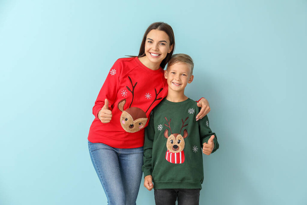 Little boy and his mother in Christmas sweaters on color background - Фото, зображення