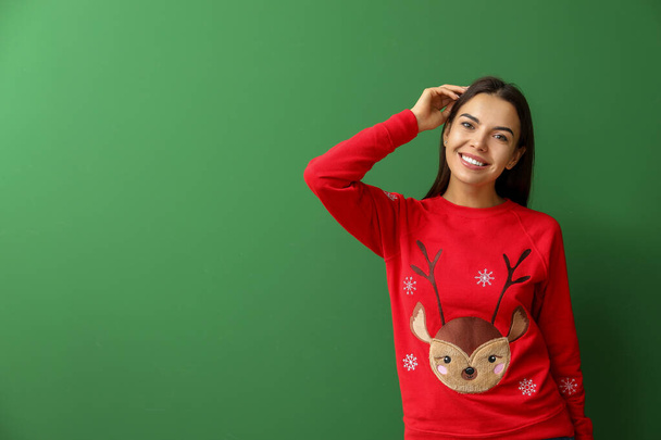 Young woman in Christmas sweater on color background - Photo, Image