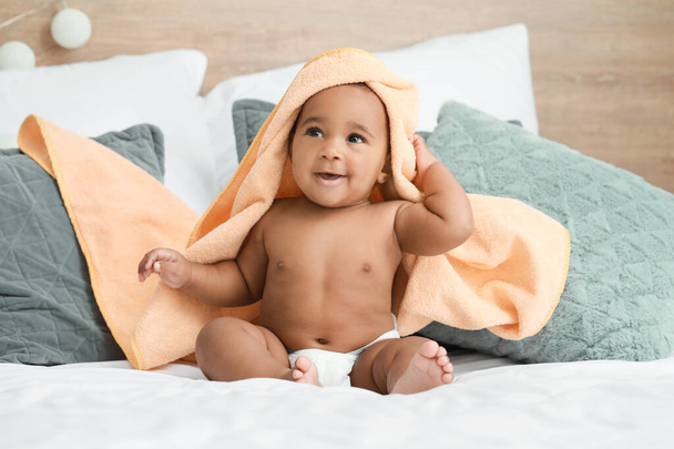 Cute African-American baby with soft towel on bed at home - Photo, Image