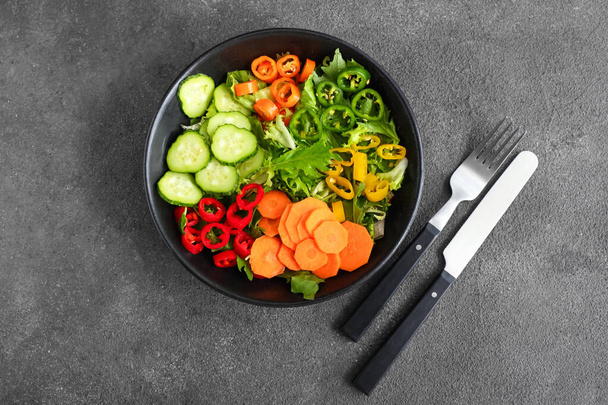 Bowl with tasty vegetable salad on grey background - Foto, afbeelding