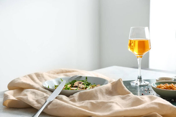 Schaal met lekkere salade en glas wijn op tafel - Foto, afbeelding