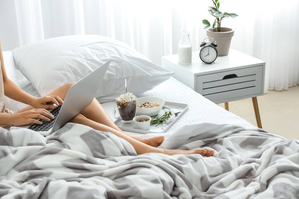 Молодая женщина с ноутбуком во время завтрака в постели
 - Фото, изображение