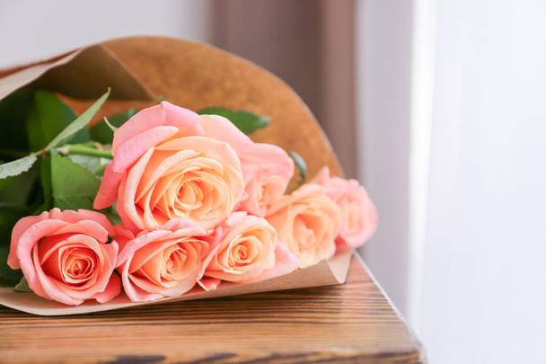 Τριαντάφυλλο λουλούδια σε ξύλινο τραπέζι στο δωμάτιο - Φωτογραφία, εικόνα