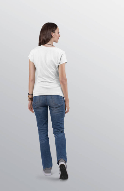 ブルーデニムジーンズパンツを着た白い無地の半袖Tシャツに美しい女性モデルを立っている。後ろの景色。隔離された背景. - 写真・画像