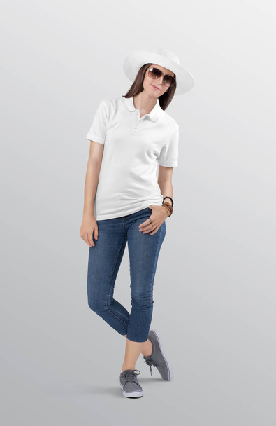 青いデニムジーンズのカプリパンツを着た白いポロシャツに女性モデルを立っています。白い夏の帽子とサングラスをかけて。隔離された背景.  - 写真・画像