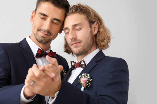 Portrait of happy gay couple on their wedding day against light background - Photo, Image
