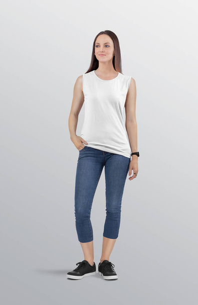 Стоїть приваблива жіноча модель в білій однотонній без рукавів сорочці з блакитними джинсовими капрі-пантерами. ізольований фон
.  - Фото, зображення