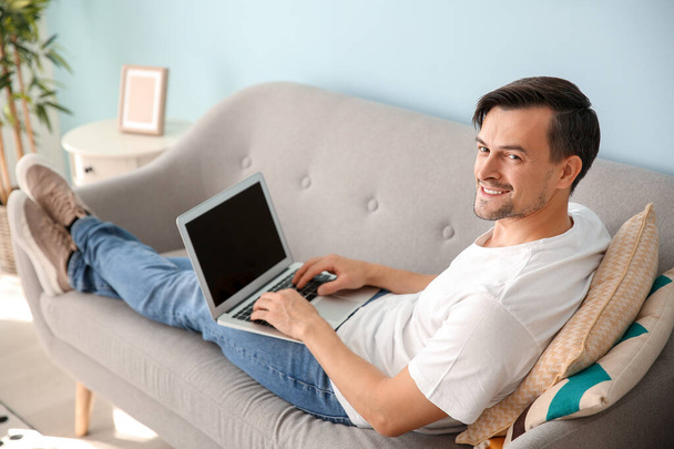 Bello uomo con computer portatile a riposo a casa
 - Foto, immagini
