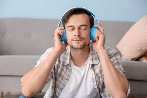 Komea mies kuuntelemassa musiikkia kotona
 - Valokuva, kuva