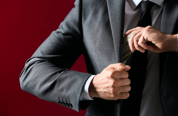 Un homme d'affaires qui met du pot de vin dans sa poche, gros plan. Concept de corruption
 - Photo, image