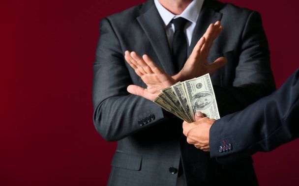 Businessman refusing to take bribe against color background - Foto, afbeelding
