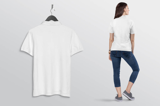 Hanging white plain polo t shirt on wall, with beautiful female model in blue denim jeans pant. Rear view. Isolated background. - Photo, Image