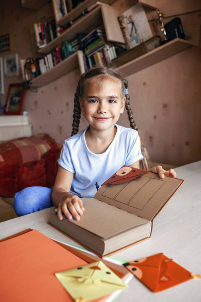 Девушка держит книгу с искусной бумажной закладкой
 - Фото, изображение