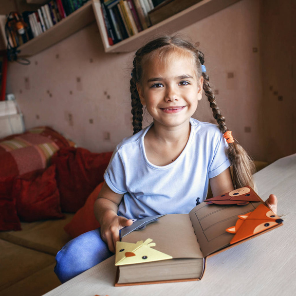 Κορίτσι που κρατά ένα βιβλίο με χειροποίητο χαρτί σελιδοδείκτη - Φωτογραφία, εικόνα