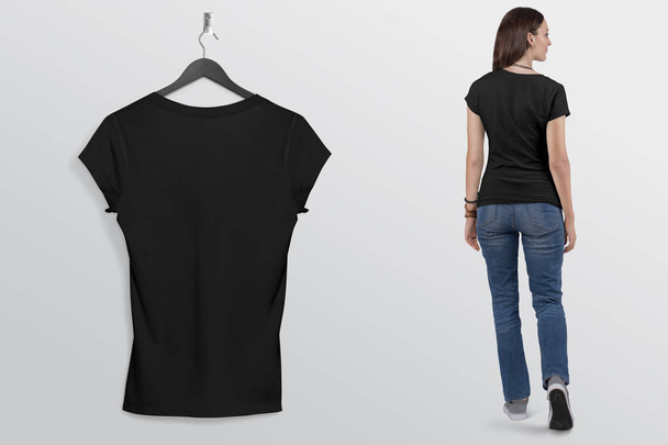 T-shirt à manches courtes uni noir suspendu au mur, avec beau modèle féminin en jean bleu pantalon. Profil arrière. Contexte isolé
. - Photo, image