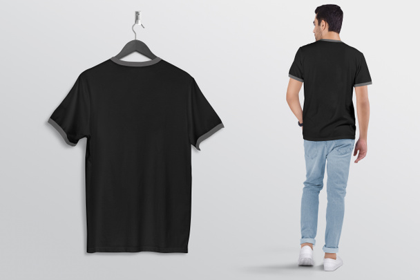 Hanging black plain ringer t shirt on wall, with male model in blue denim jeans pant. Back view. Isolated background.  - Photo, Image