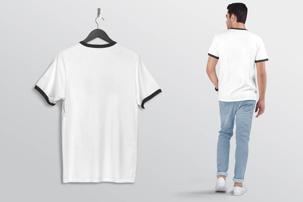 An der Wand hängt ein weißes, schlichtes Ringer-T-Shirt, dazu ein männliches Modell in blauer Jeanshose. Rückseite. isolierter Hintergrund.  - Foto, Bild