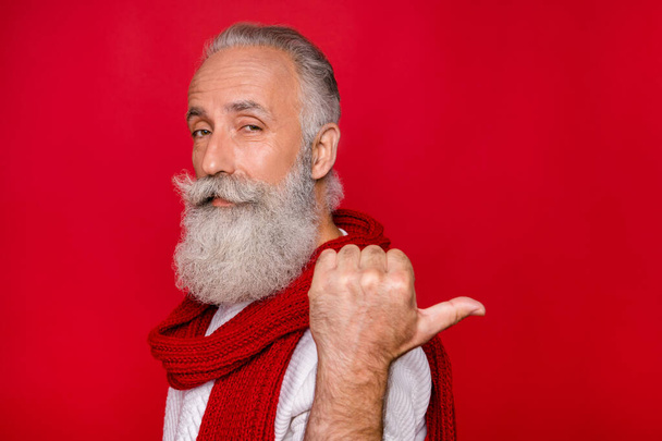 Portrait of confident pensioner pointing at ads following wearing white jumper isolated over red background - Photo, Image
