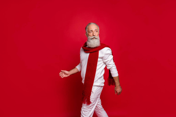 Portrait of classy retired man walking looking wearing white pullover pants trousers isolated over red background - Zdjęcie, obraz
