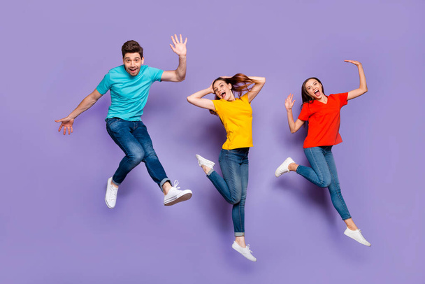 Full length size body photo of two beautiful carefree cheerful excited ladies and one comic funny in blue t-shirt guy waving hand saying hello isolated violet background - Valokuva, kuva