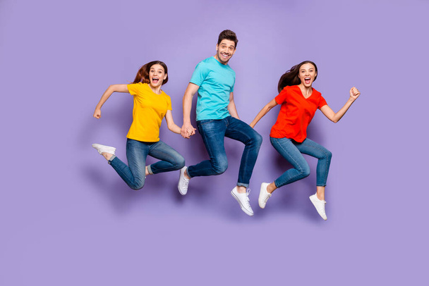 Full length size body photo of three excited cheerful crazy unstoppable actively moving victorious successful freelancers group of millennials holding hands isolated violet background - Fotoğraf, Görsel