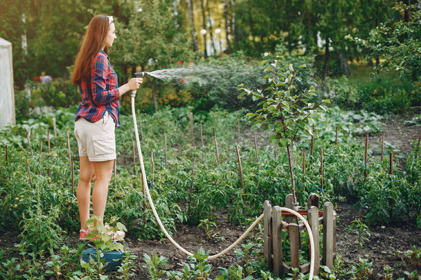 Beautiful woman works in a garden near the house - Фото, изображение