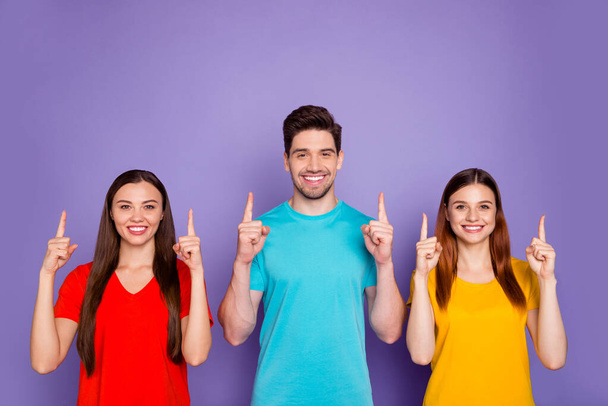 Photo of three charming cheerful confident group of people directing forefingers over heads isolated violet background - Zdjęcie, obraz