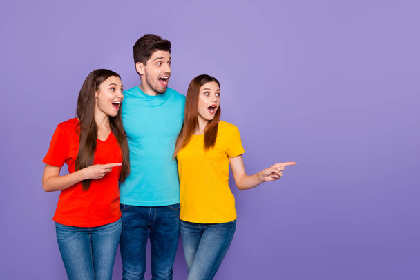 Portrait of nice attractive lovely amazed astonished cheerful cheery glad guys wearing colorful t-shirts denim pointing aside look new idea ad advert isolated over violet lilac background - 写真・画像