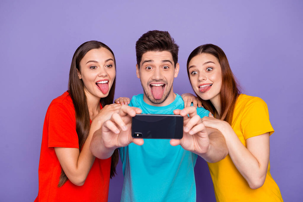 Portrait of three nice attractive lovely charming crazy childish cheerful cheery glad guys wearing colorful t-shirts taking making selfie having fun isolated over violet lilac background - Valokuva, kuva