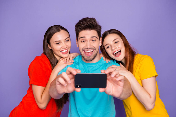 Portrait of three nice attractive lovely cheerful cheery glad guys wearing colorful t-shirts taking making selfie having fun blog blogger post smm isolated over violet lilac background - Fotó, kép