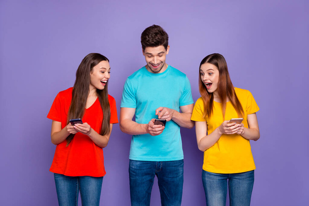 Portrait of nice attractive lovely charming cheerful cheery glad guys wearing colorful t-shirts jeans surfing web site browsing 5g app news game free time isolated over violet lilac background - Фото, зображення