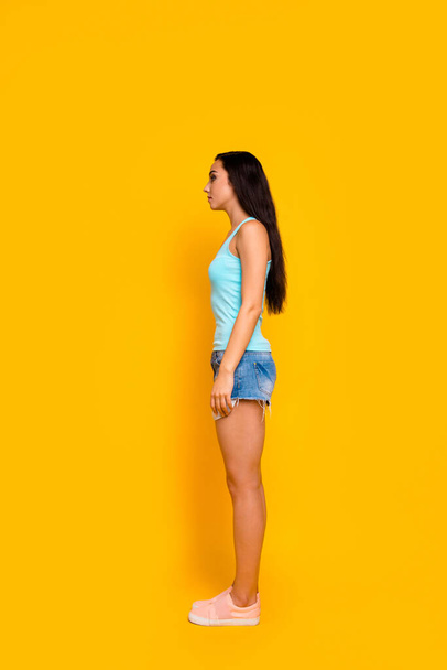 Vertical full length body size side profle photo of girl staring away wearing jeans denim shorts sneakers isolated over bright color background - Fotoğraf, Görsel