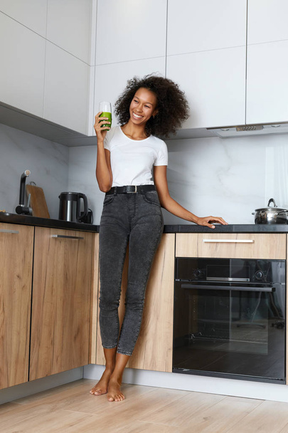 Woman drinking green detox juice, smoothie drink in kitchen - Zdjęcie, obraz