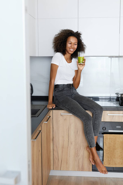 Woman drinking green detox juice, smoothie drink in kitchen - Photo, image