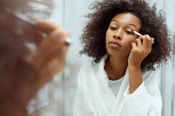Beauty makeup. Woman applying cosmetics on eyes at bathroom - Фото, изображение