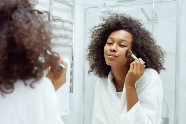 Beauty makeup. Woman applying cosmetics on face at bathroom - Zdjęcie, obraz