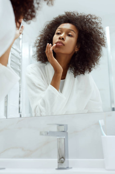 Lips skin care. Woman applying lip balm in bathroom portrait - Fotoğraf, Görsel