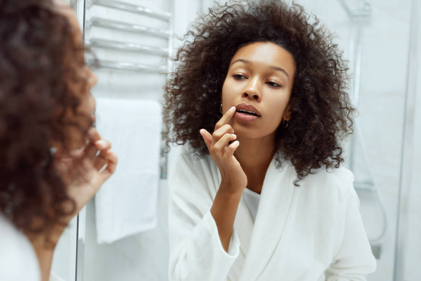 Lips skin care. Woman applying lip balm in bathroom portrait - Fotoğraf, Görsel