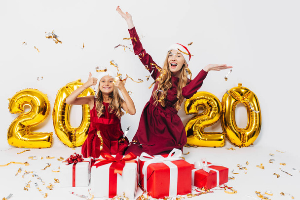 Happy excited mom with a little daughter, in Santa hats, cheerfu - 写真・画像