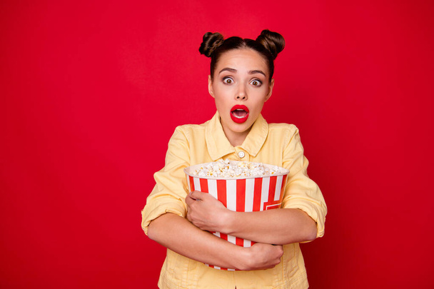 Pretty lady holding popcorn container watching horror movie wear casual outfit isolated red background - Foto, Imagen