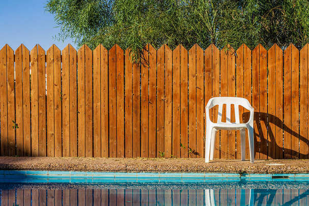 hátsó udvar külvárosi villa pihenőhely medencével műanyag fehér szék és fa fedélzet kerítés háttér  - Fotó, kép