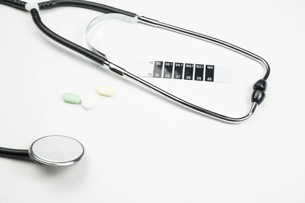medical stethoscope, medication and thermometer-strip on white i - Foto, Imagem