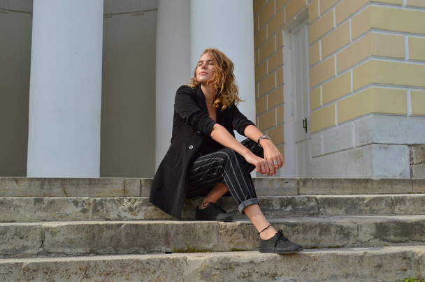 Una joven sexy en un traje negro de negocios está sentada
 - Foto, Imagen