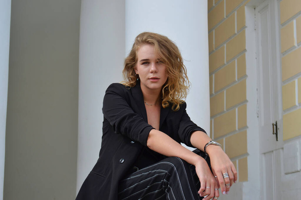 Uma jovem mulher sexy em um terno preto de negócios está sentada
 - Foto, Imagem