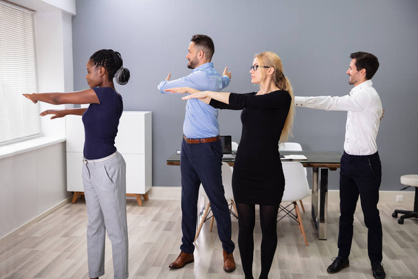 Happy Businesspeople Standing In A Row Doing Exercise With Hands Outstretched At Office - Fotó, kép