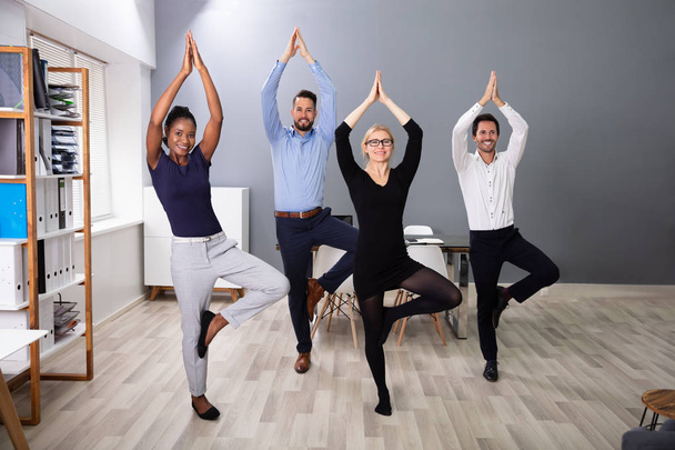 Happy Businesspeople Standing In A Row Doing Exercise With Hands Outstretched At Office - Foto, immagini
