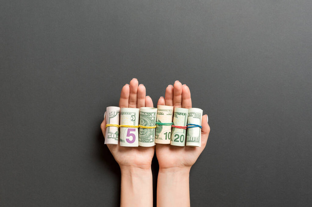 Bovenaanzicht van dollarbiljetten opgerold in buizen in vrouwelijke handpalmen op zwarte achtergrond. Pensioenconcept - Foto, afbeelding