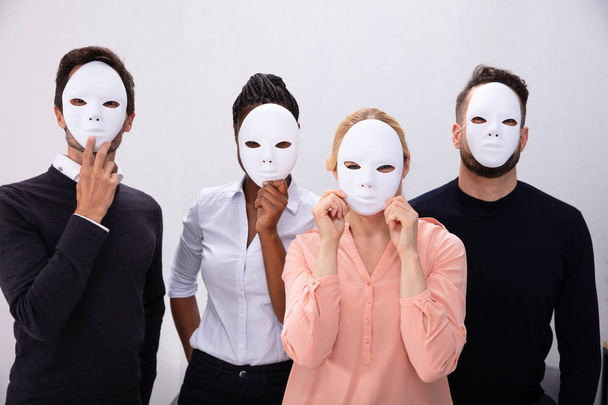grupo de personas de pie juntos cubriendo su cara con máscaras blancas
 - Foto, imagen
